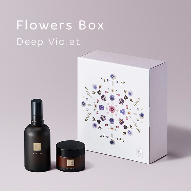 紫色の背景に「Flowers Box Deep Violet」のテキストにN organic Vieのローション、クリームの商品と花形デザインのギフトの箱の写真
